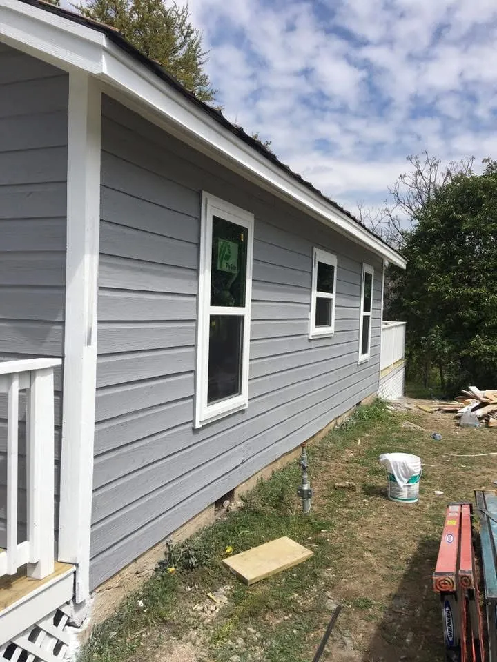 Side of the cottage showing fresh gray lap siding and white window trim