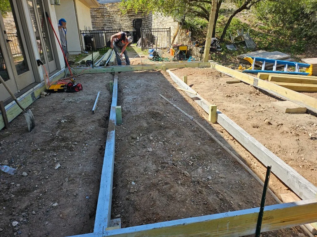 Bare ground behind the house with the deck frame being laid out and leveled