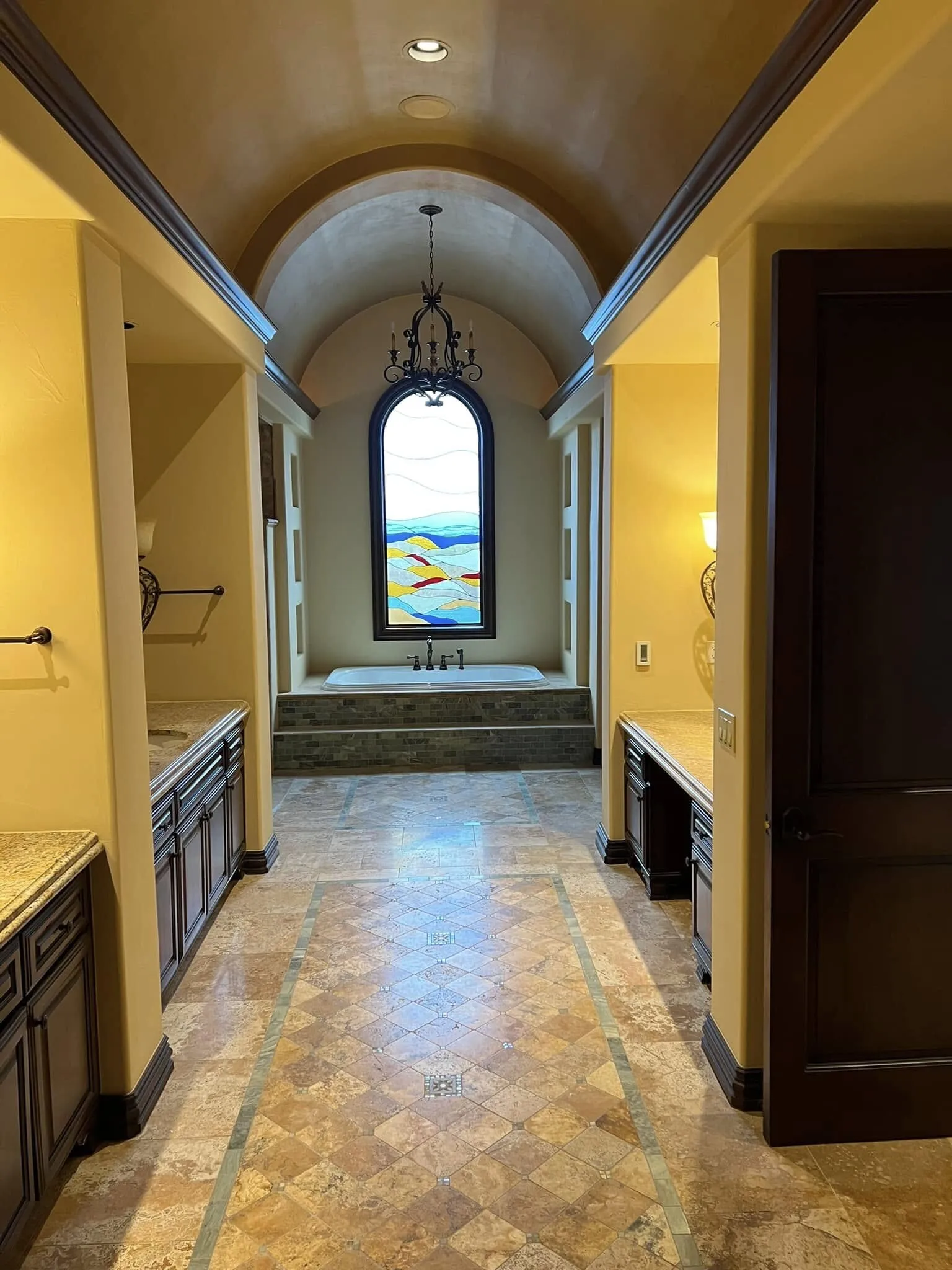 Arched hallway leading to a stained-glass window, painted in warm gold