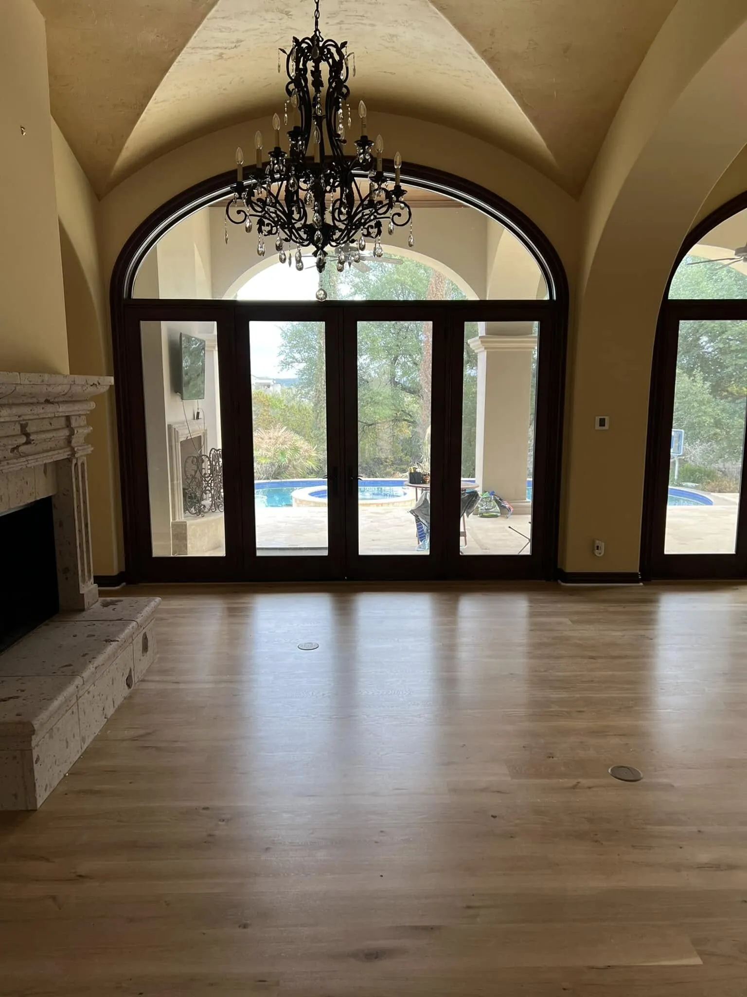 Great room with arched windows, a chandelier and light wood floors, freshly painted in warm cream
