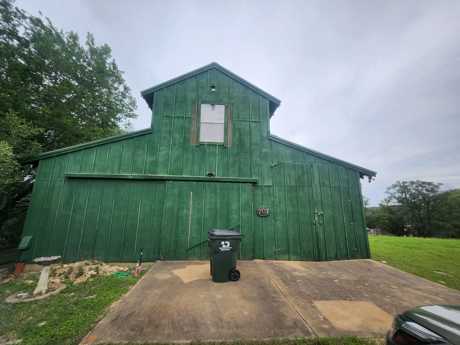 Two-story green board-and-batten barn with a center gable and sliding doors