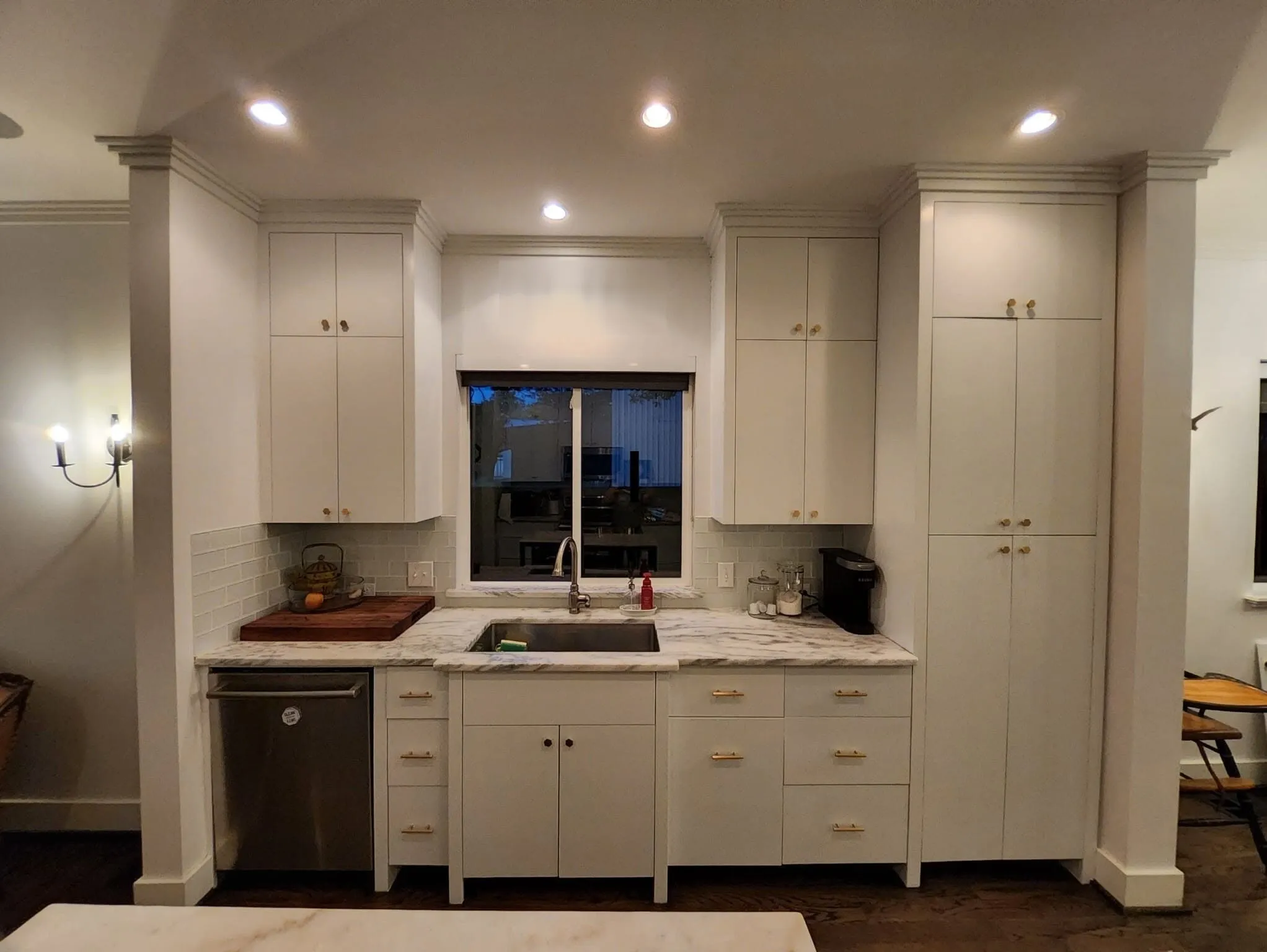 The same kitchen after, cabinets painted white with new brass pulls