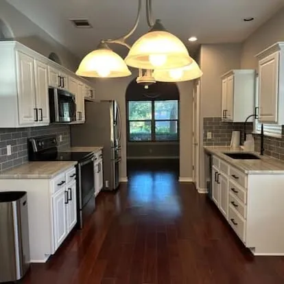Range wall of the same kitchen with white cabinets and a gray subway-tile backsplash