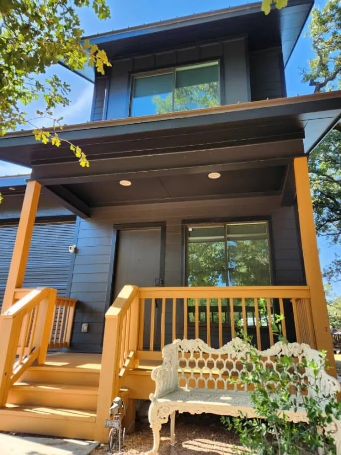Close view of the cedar-toned porch posts and railing against the charcoal siding