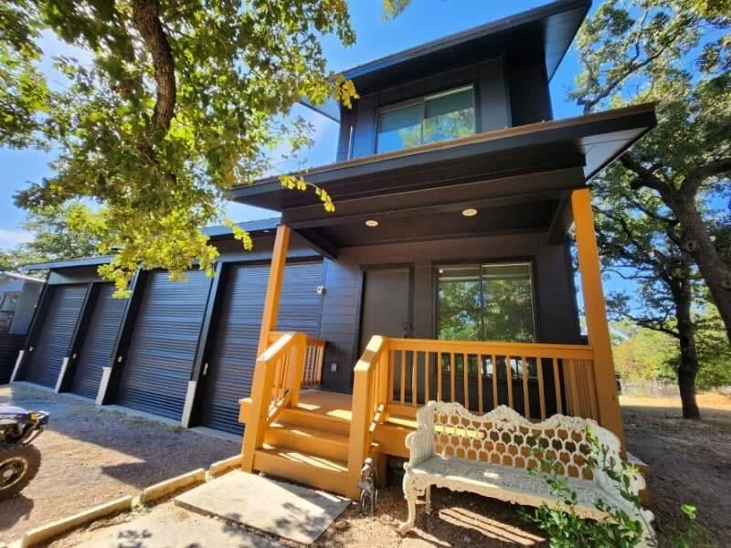 Modern two-story home painted charcoal with black trim and a cedar-colored porch and railing