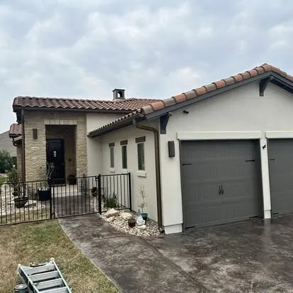 Spanish-style stucco home with a tile roof and fresh paint on the garage door and trim