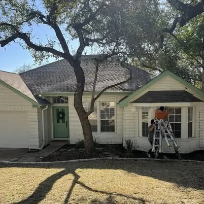 The same home mid-project, with the old green trim and a ladder at the front window